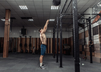 Obraz na płótnie Canvas Athletic male bodybuilder exercises with medicine ball in the gym. Functional training