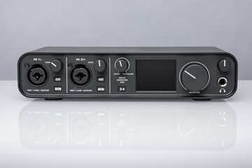 USB Audio interface for home recording or Mixing, external sound card black on white glass with reflection.