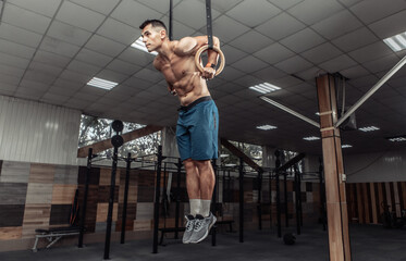 Muscular male gymnast exercising on gymnastic rings in a modern health club. Healthy lifestyle...