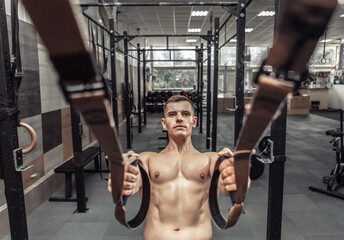 Fototapeta na wymiar Muscular man exercising with the trx resistance system in a modern cross-fit club. Functional training
