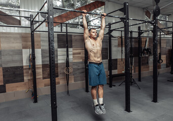 Muscular man exercising with the trx resistance system in a modern cross-fit club. Functional training