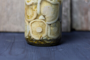 Salty white milk mushrums in rlass jar on wooden background