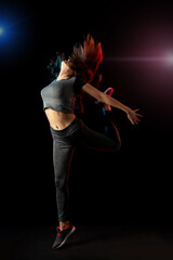 Young slim sports girl  jumping on black background.