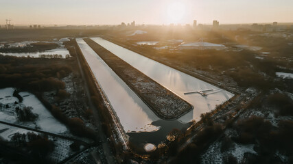 A beautiful rowing channel with frozen water. City landscape in the evening. A reservoir of unusual shape. Sunset in Moscow