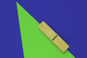 Modern tv remote in a case on colored paper background with geometric shapes. Top view. Fashion concept