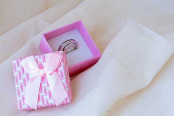 Pink box with wedding rings on a white linen cloth. Concept love, wedding, romance, Valentine's Day. Space for writing.
