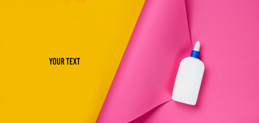 Bottle of glue on a color studio paper background with space for your text. Top view