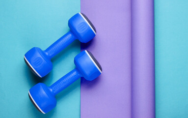 Blue plastic dumbbells on wrapped paper background. Color trend, minimalistic sport and fashion...