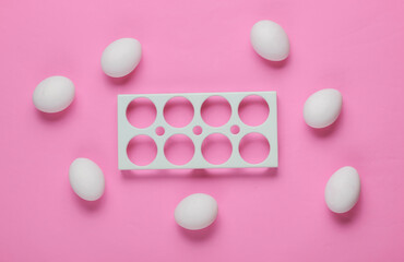 Empty tray and chicken eggs on pink background. Minimalism food concept. Top view