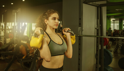 Fototapeta na wymiar Athletic young fit woman doing exercise with kettlebells in the gym. Free weights, functional training