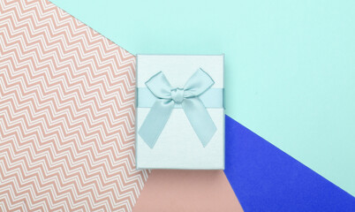 Gift box with bow on a colored background. Pastel color trend. Top view