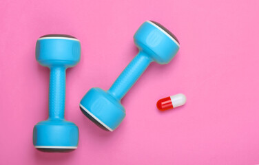 Pharmacology in sports. Dumbbell and capsule on pink background. Vitamins, steroids. Top view