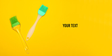 Kitchen spatula and brush on yellow background with space for text. Top view