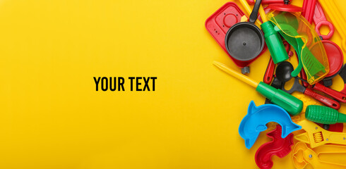 Copy space with lot of children's toys on yellow background. Space for your text. Childhood concept. Top view