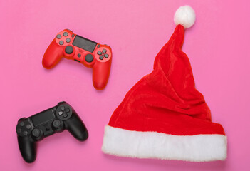 Gamepads with santa hat on pink background. Top view © splitov27