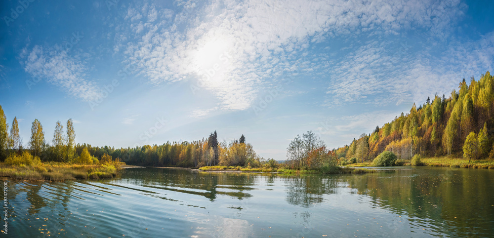 Wall mural autumn forest trees are reflected in the river water of the panoramic landscape. blue sky with cloud