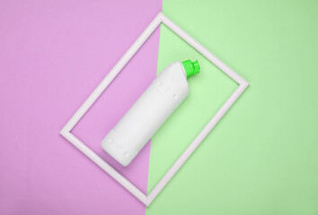 Bottle of detergent on a pink-green pastel background with a white frame. Top view. Minimalism