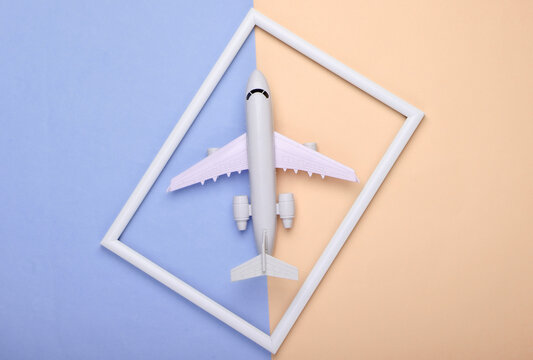 Airplane in a white frame on pink blue pastel background. Travel concept. Top view. Flat lay