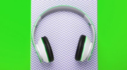 Stylish wireless stereo headphones on colored neon background. Music lover. Gadgets. Top view.