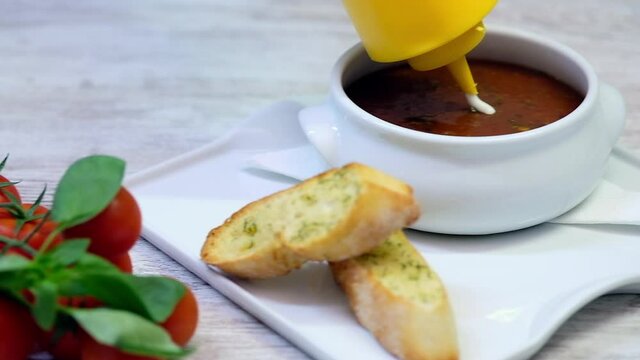 Close up view chef decorating finish preparation of goulash soup serve topping with sour cream or with the yogurt on white plate served with crouton. Main course dish. Restaurant food concept