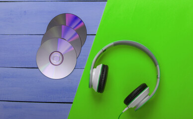 Stereo headphones, cd discs on blue wooden table. Music lover. Retro 90s. Top view.