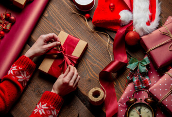Fototapeta premium Woman wrapping gift on wooden table