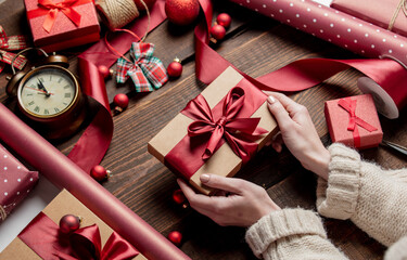 Woman wrapping gift on wooden table - obrazy, fototapety, plakaty