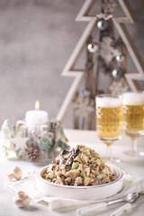 New year table. Festive salad with chicken, cucumbers, mushrooms, prunes, eggs and mayonnaise in a white plate with glasses of champagne. Birch salad. Background image, copy space, vertical