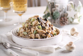 New year table. Festive salad with chicken, cucumbers, mushrooms, prunes, eggs and mayonnaise in a white plate with glasses of champagne. Birch salad. Background image, copy space, horizontal