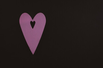 Pink heart on black background. Love symbol. Pink wooden heart with black copy space. Valentine day concept. Romantic background. Heart in heart isolated. 
