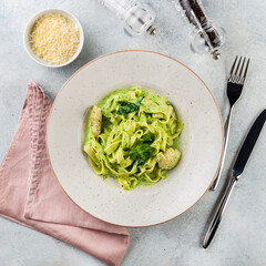 Pasta Tagliatelle with spinach pesto sauce and fresh basil leaves in a white platel. light background.