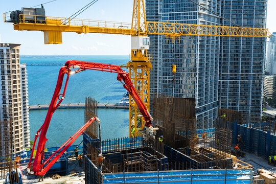 Tower crane and concrete hydraulic pump at work elevating a high rise to a new floor during contractor period of construction in brickell downtown Miami Florida USA