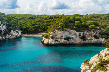 Views of Cala Macarelleta, in Minorca, with blue turquoise waters in a cloudy day