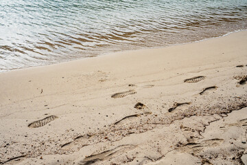 Fototapeta na wymiar Footprints in the sand, near the shore, with calm waters beach, in Minorca
