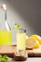 Traditional Italian liqueur Limoncello. Glass bottle with homemade Limoncello liqueur, plate with lemons and celery.