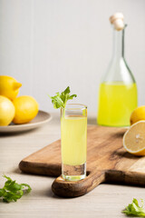 Traditional Italian liqueur Limoncello. Glass bottle with homemade Limoncello liqueur, plate with lemons and celery.