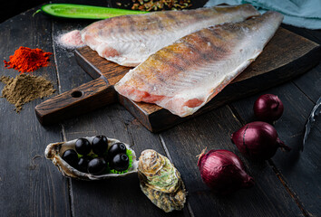 Fresh pikeperch fillet with cooking ingredients on a wooden cutting board. Top view. 