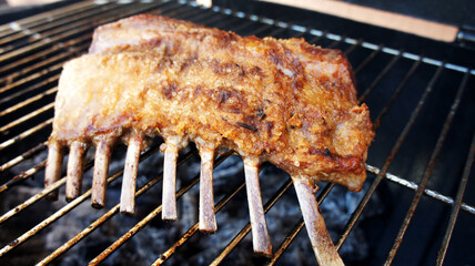 French Rack or Lamb Ribs. Grilled in barbecue in wood background