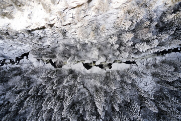 Flying over winter wonderland with frozen creeks and snow clothed trees. Shot with a drone in...