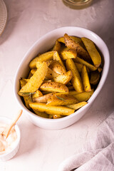 Slices of baked potatoes with rosemary and oil in a bowl