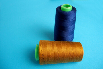 two large new skeins of blue and orange denim thread stand on a blue background side view