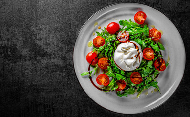 salad with burrata cheese, arugula salad and tomatoes on plate
