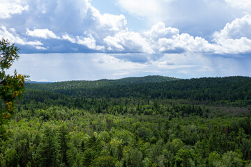 Fototapeta na wymiar Landscape of green forest hills below clouds