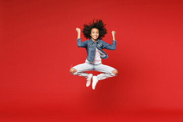 Full length of joyful little african american kid girl 12-13 years old in denim jacket jumping...