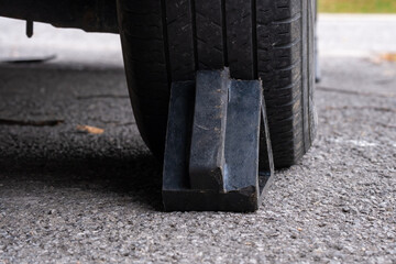 Fototapeta na wymiar Black wheel chock holding rear rubber tire