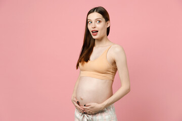 Happy young pregnant woman future mom in basic top stroking keeping hands on big belly stomach tummy with baby isolated on pastel pink background studio. Maternity family pregnancy gynecology concept.