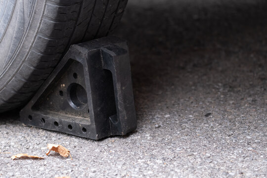 Black rubber wheel chock behind car tire