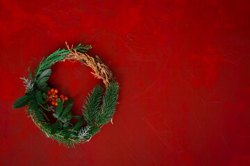  christmas wreath with fir and spruce branches and hawthorn on red wooden background top view photo