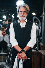 Fototapeta na wymiar In barbershop. Stylish modern senior man with gray hair and beard is indoors