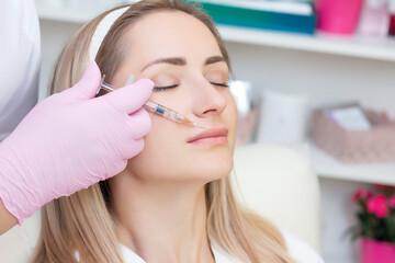 young woman receiving cosmetic injection. Woman in a beauty salon. Plastic Surgery Clinic.